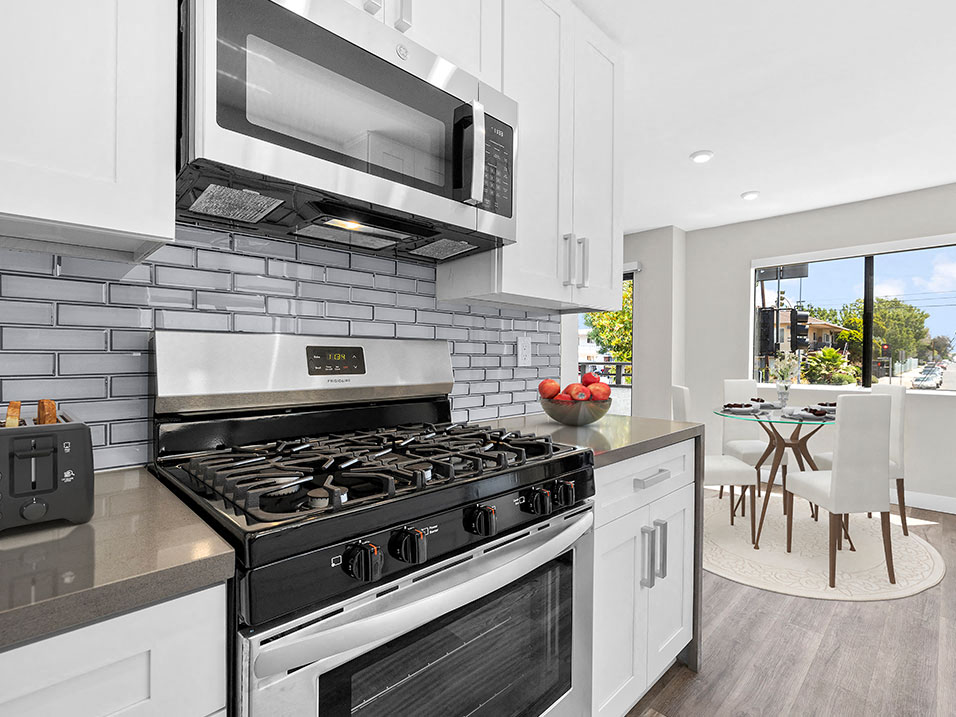 Blue tiled kitchen with stainless steel oven, microwave, and fridge.