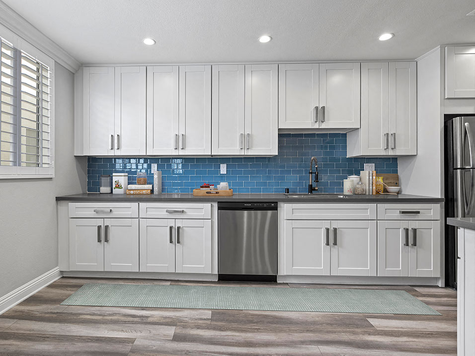 Blue tiled kitchen with stainless steel dishwasher and fixtures.