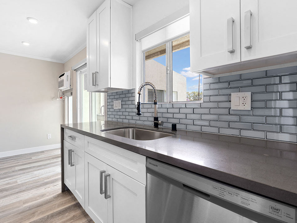 Blue tiled kitchen with stainless steel oven, fridge, dish washer, and fixtures.