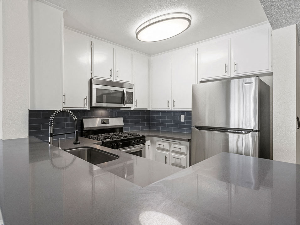 Kitchen with stainless steel oven, microwave, and fridge.