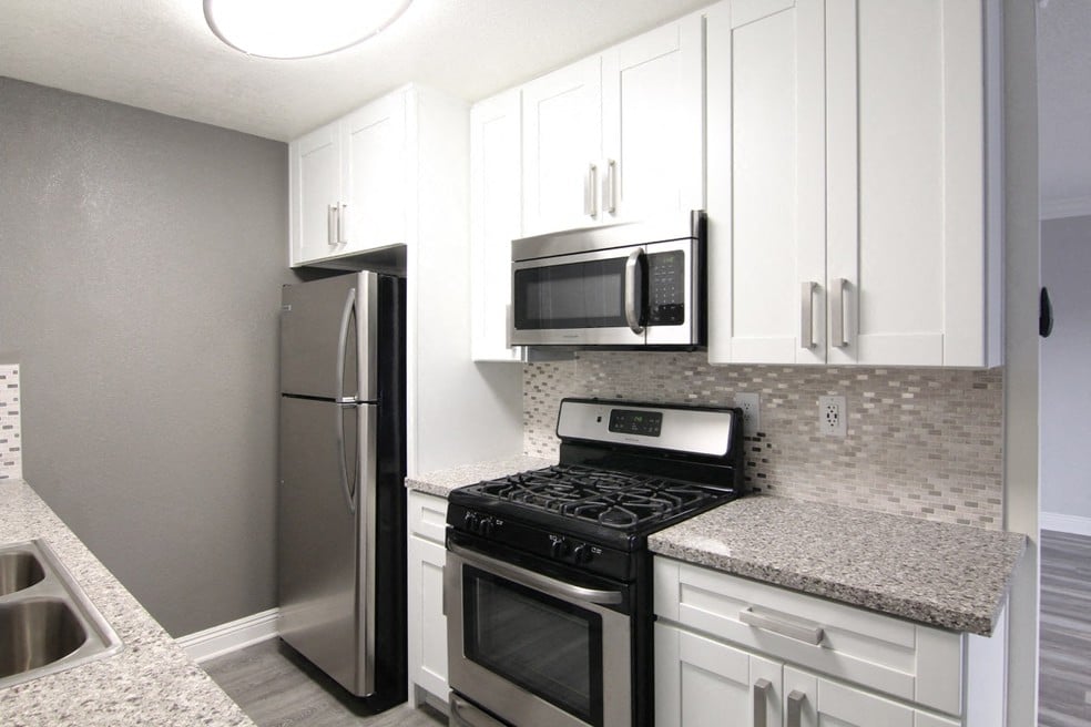 Kitchen with quartz stone counters and stainless steel microwave, oven, fridge, and fixtures.