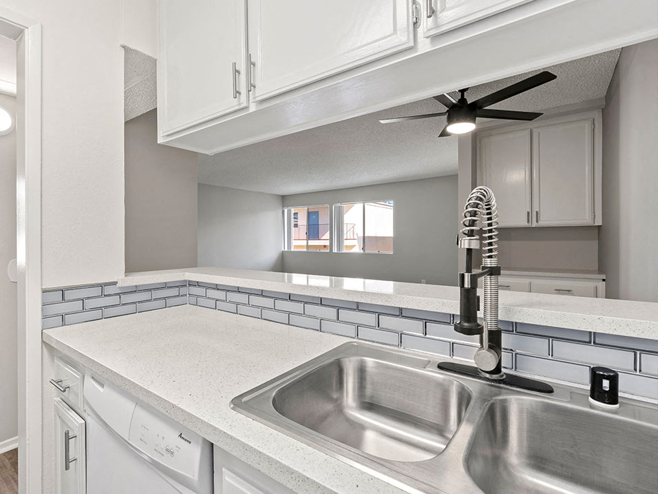 White tiled kitchen with stainless steel farmhouse style sink.