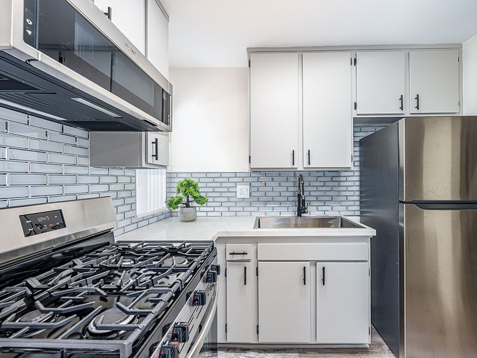 Tiled kitchen with stainless steel fridge, oven, and miocrowave.