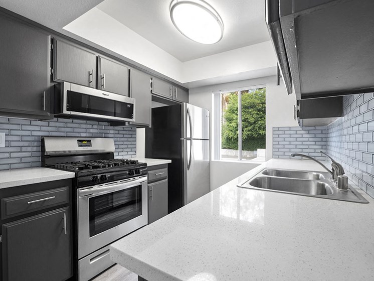 Tiled kitchen with stainless steel oven, microwave, and fridge.