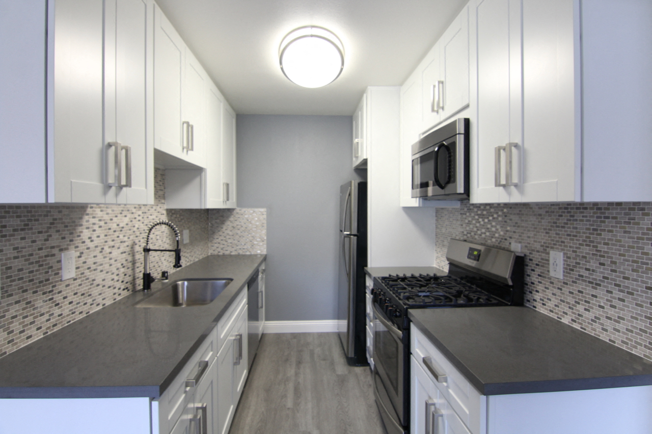 Kitchen with quartz stone counters and stainless steel microwave, oven, fridge, and fixtures.