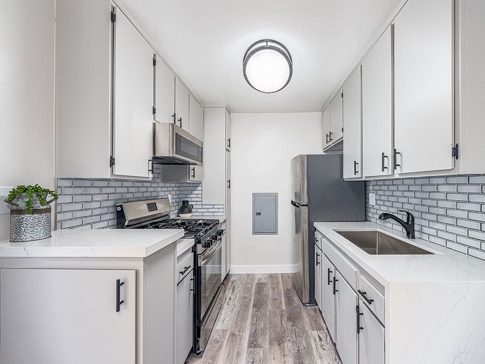 Tiled kitchen with stainless steel fridge, oven, and miocrowave.
