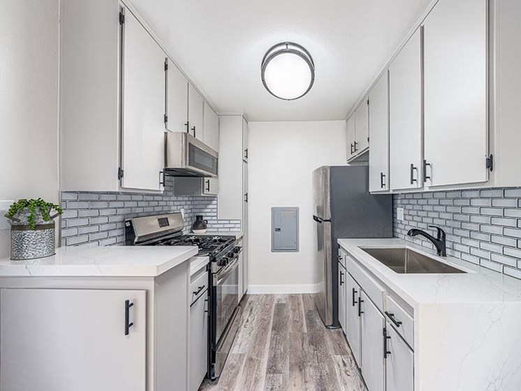 Tiled kitchen with stainless steel fridge, oven, and miocrowave.