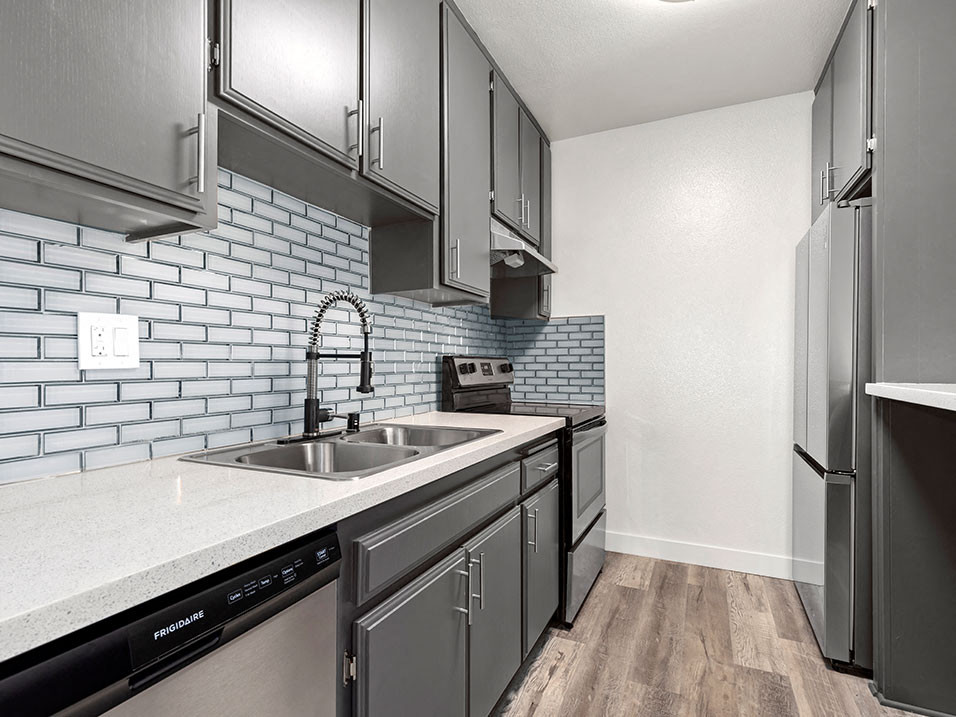 White tiled kitchen with stainless steel fridge, microwave, and oven.