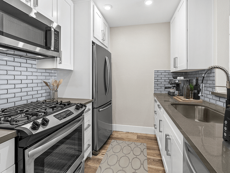 Glass tiled kitchen with stainless steel fridge, oven, and microwave.