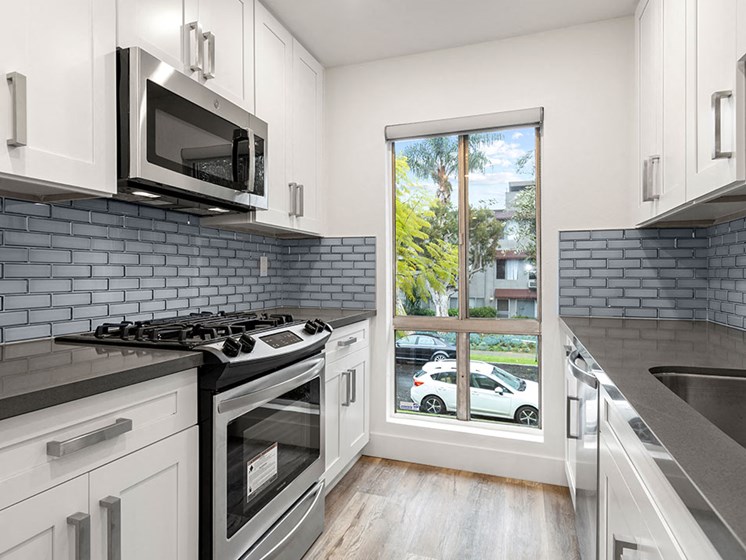 Blue tiled kitchen with stainless steel microwave, oven, and fixtures.