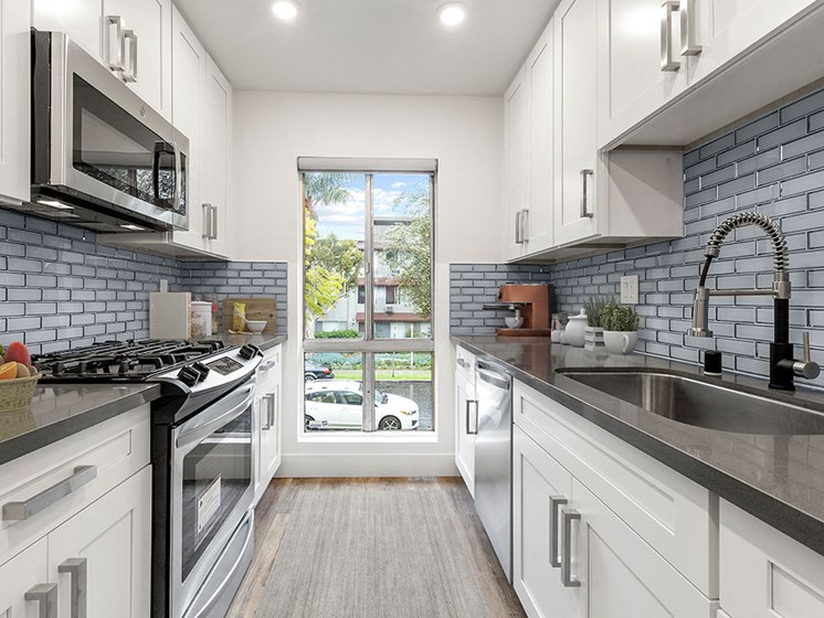 Blue tiled kitchen with stainless steel microwave, oven, and fixtures.