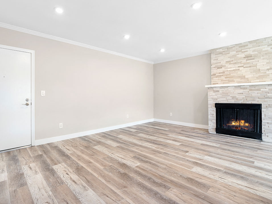 Hardwood floored living room with stone accented fireplace.