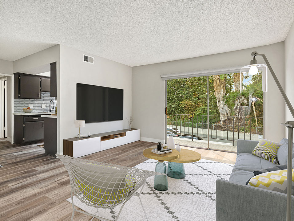 Hardwood floored living room with view of balcony and kitchen.
