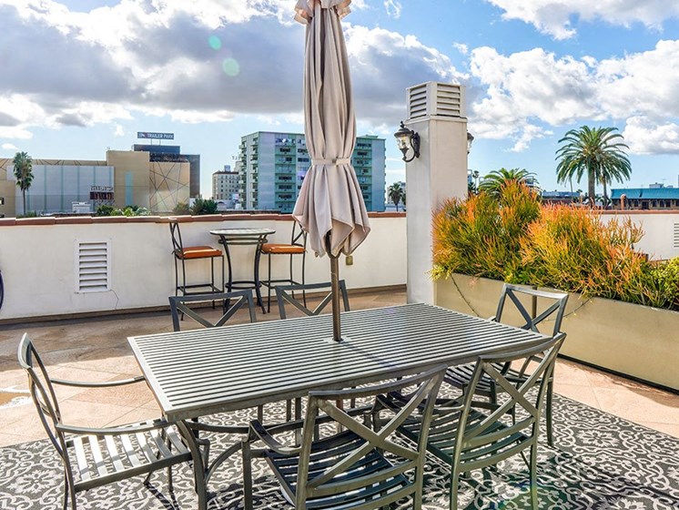 Open air rooftop patio with gas firepit, BBQs, several seating locations, and cable television.