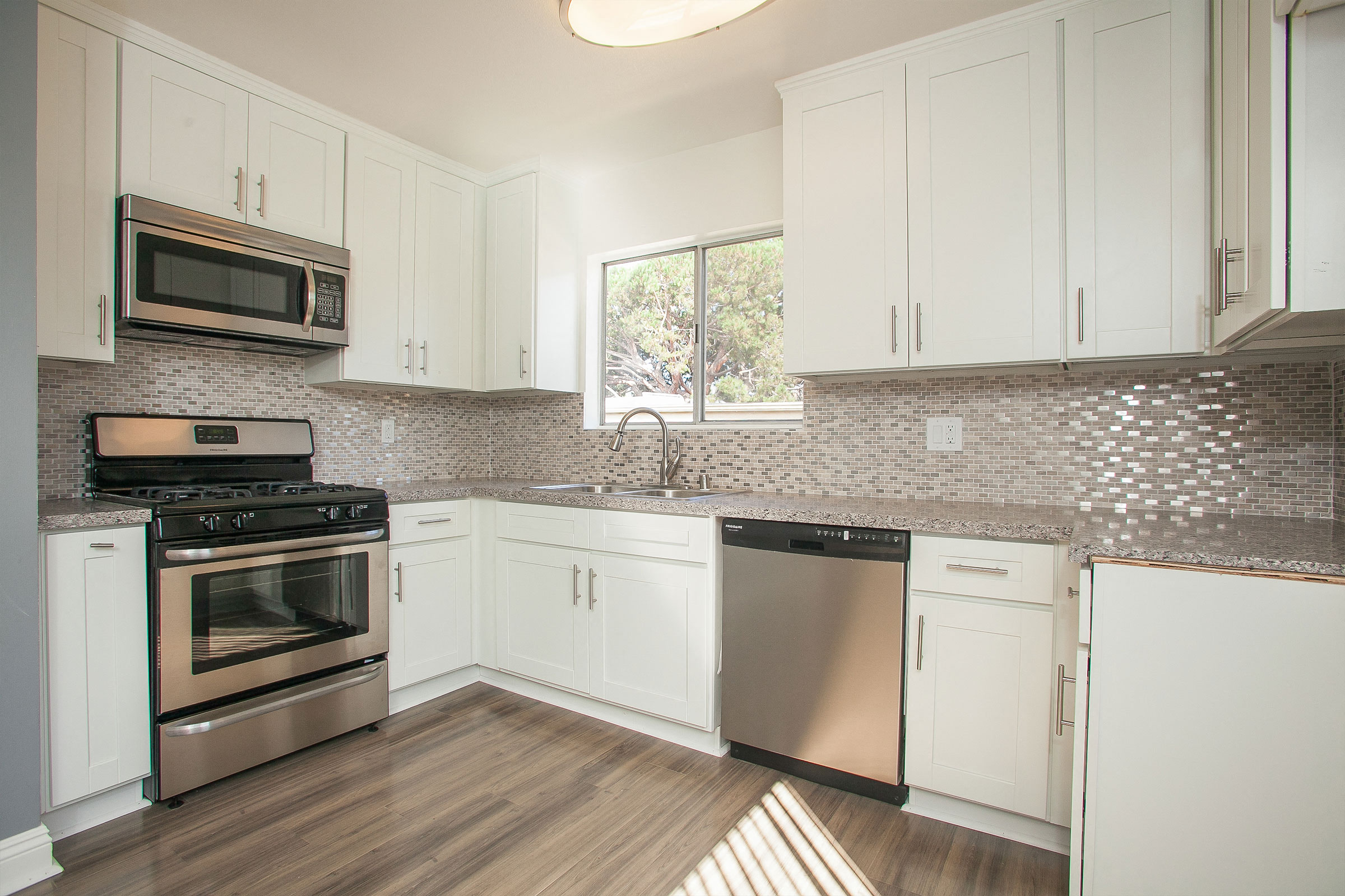 Large kitchen with new cabinets, stainless steel appliances, quartz stone counters, and modern backsplash.