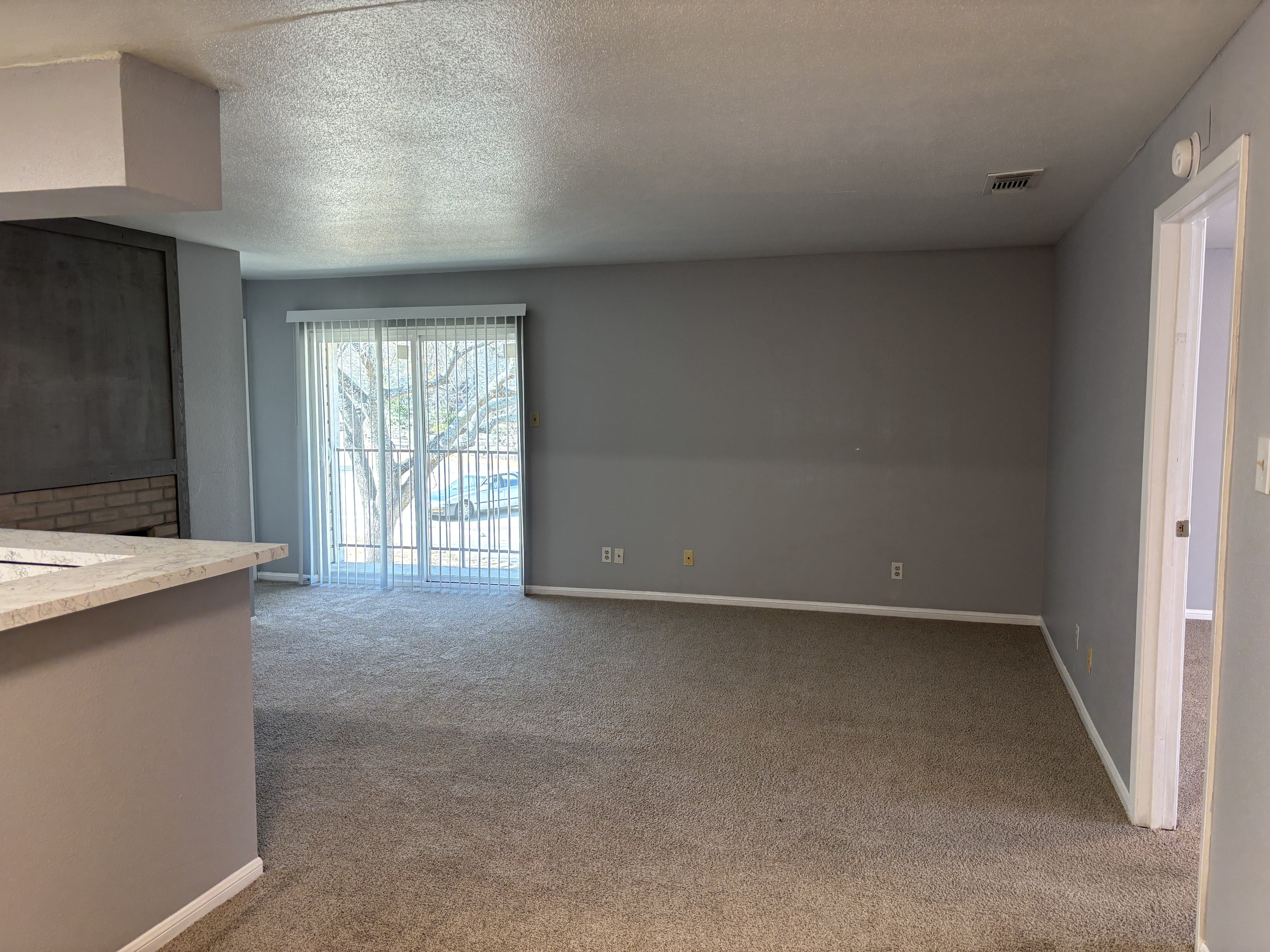 A room with a carpeted floor and a window with blinds.