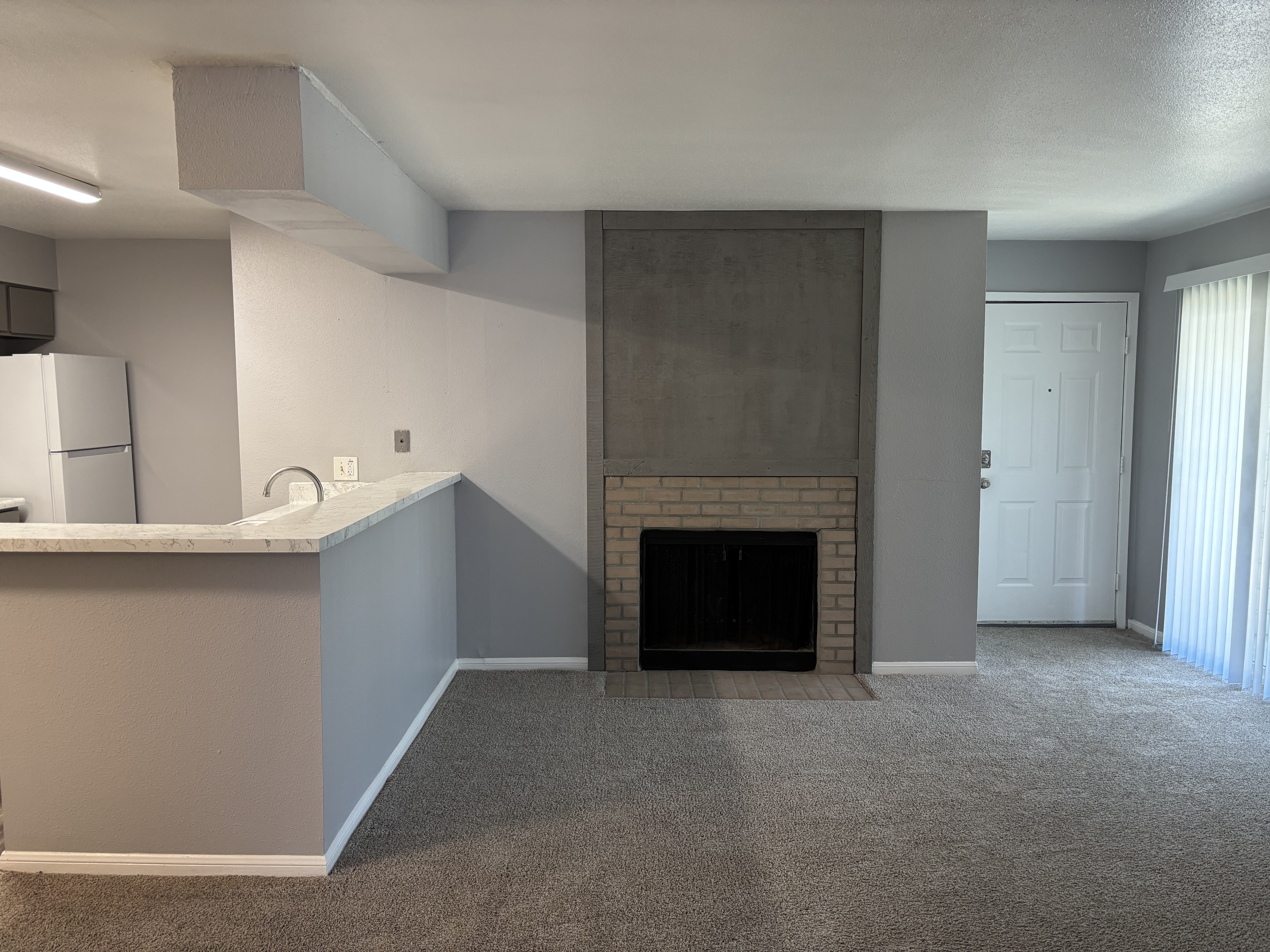 A room with a fireplace and a refrigerator.