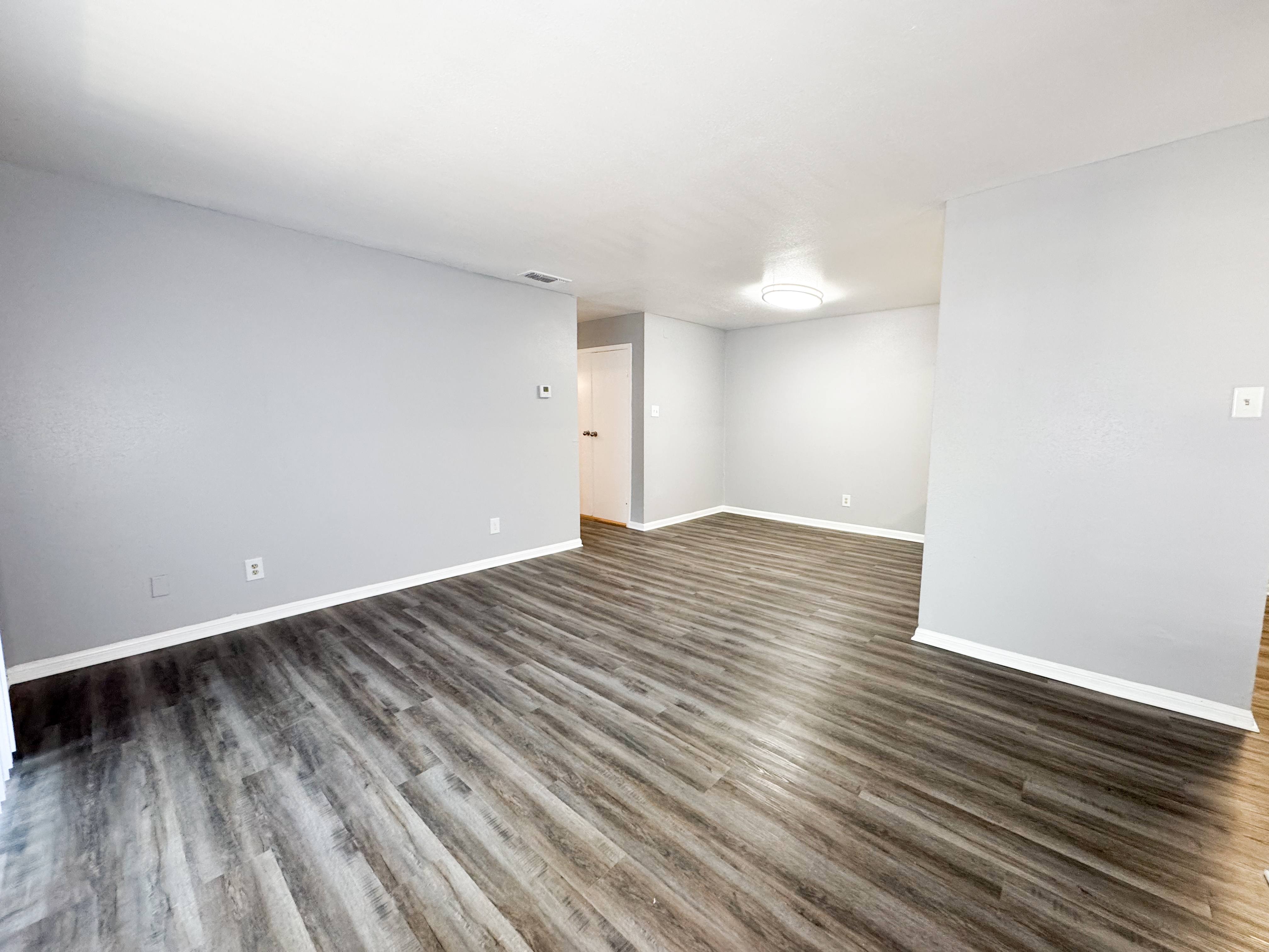 A room with wooden flooring and white walls.