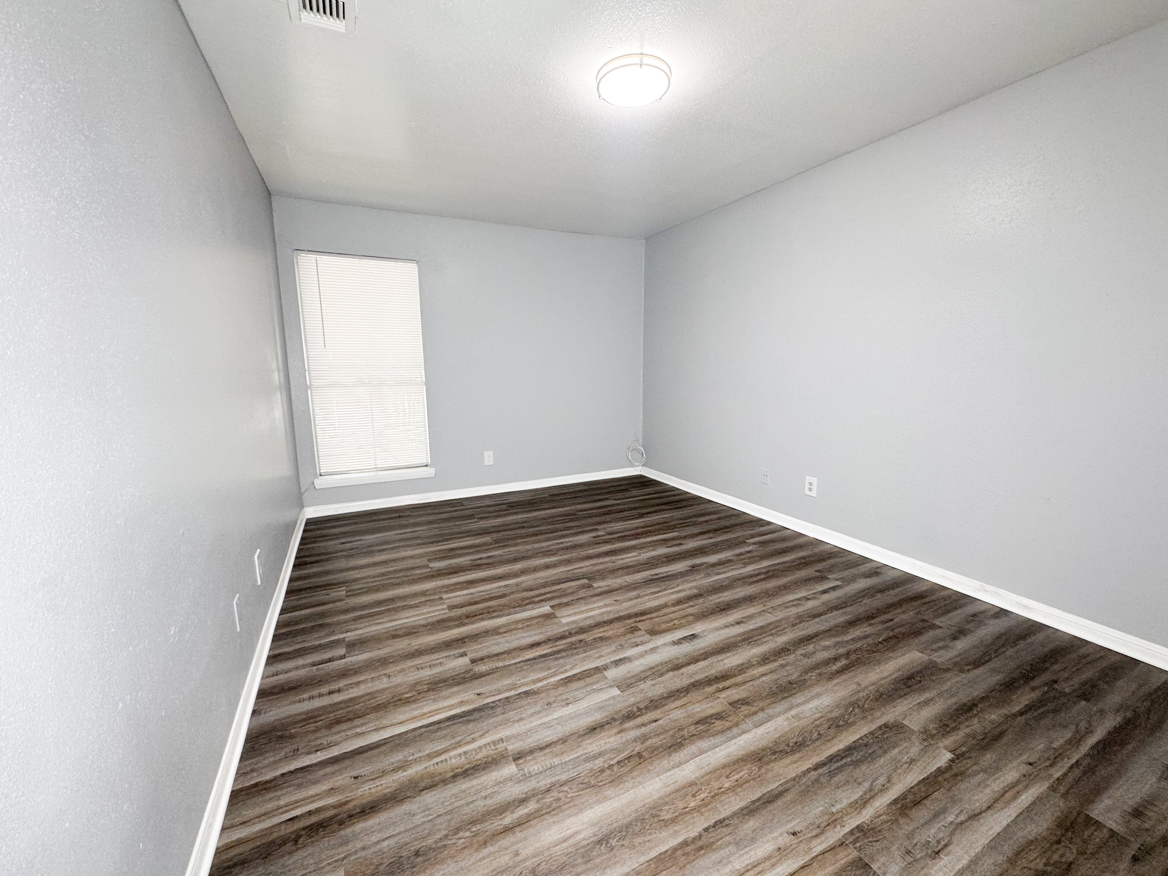 A room with wooden flooring and a window.