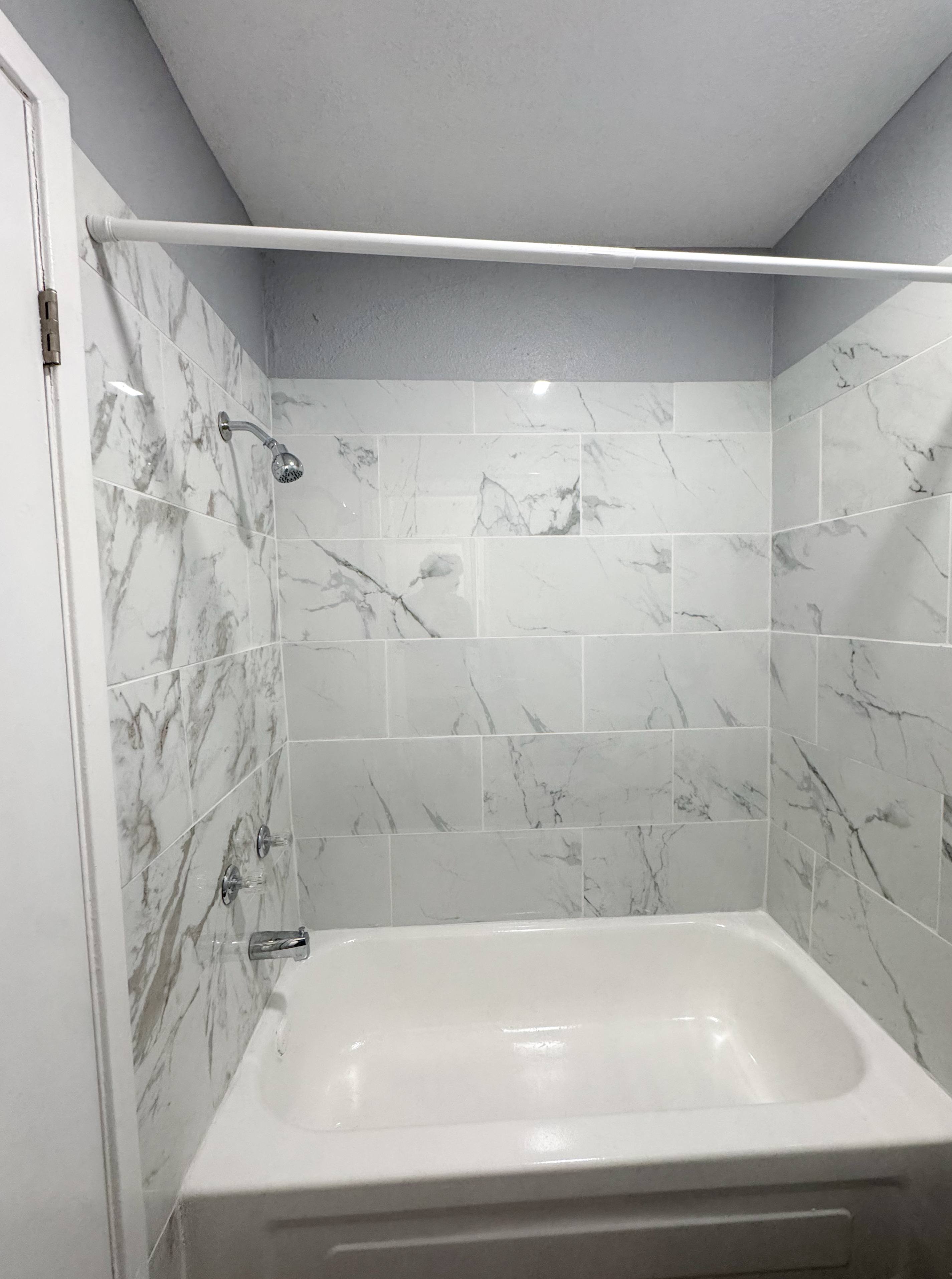 A white bathroom with a marble tile wall.