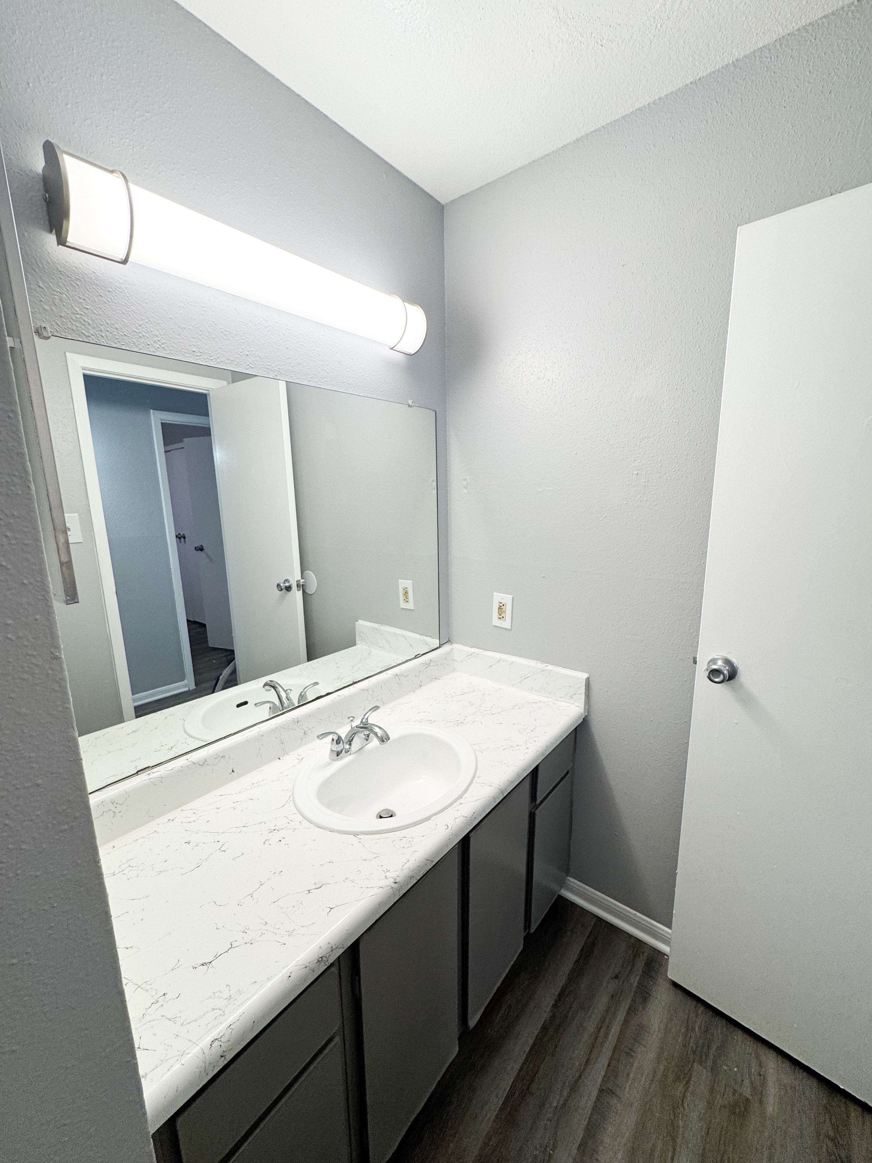 A bathroom with a white counter top and a white sink.