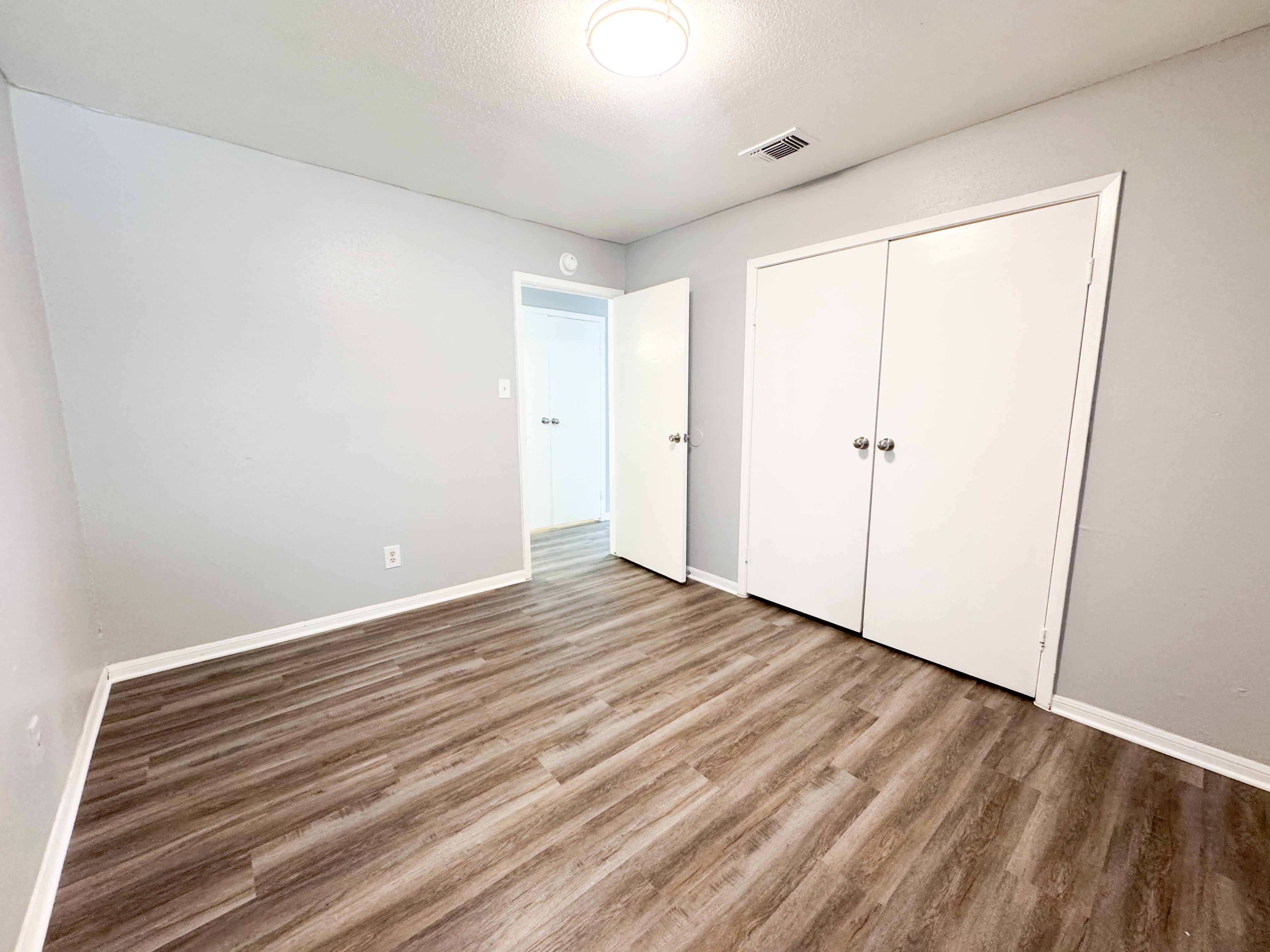 A room with a white door and two white cupboards.