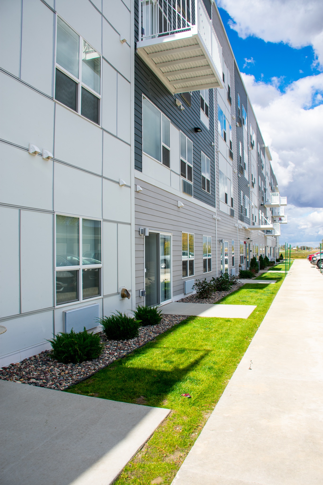 A long building with a lot of windows and a green strip down the side.,A long building with a lot of windows and a green strip down the side.