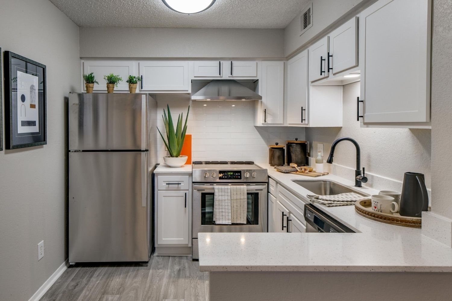 Bright kitchen with white shaker cabinets, stainless appliances, and quartz peninsula seating.