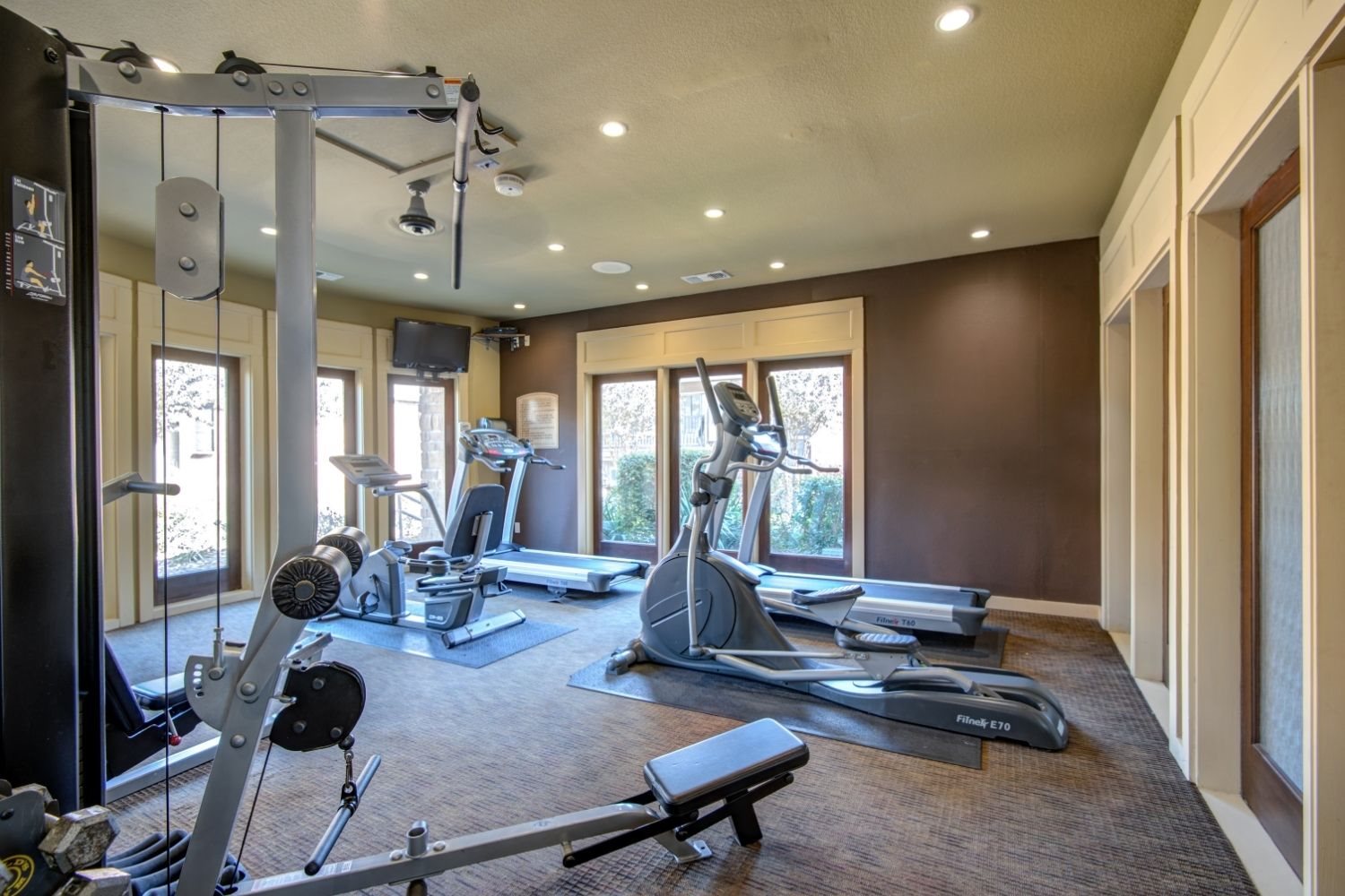 Fitness center with treadmills, elliptical machines, and strength equipment in a bright room