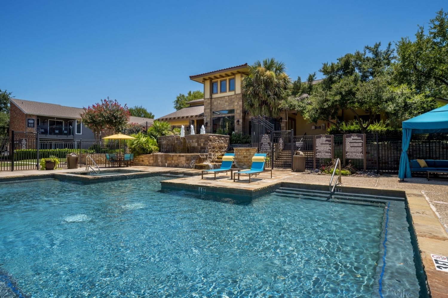 Resort-style pool with tanning ledge, lounge chairs, and landscaped courtyard views.