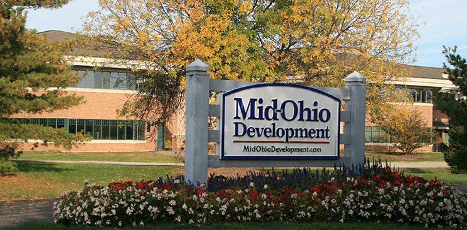 A sign for Mid Ohio Development in front of a building.