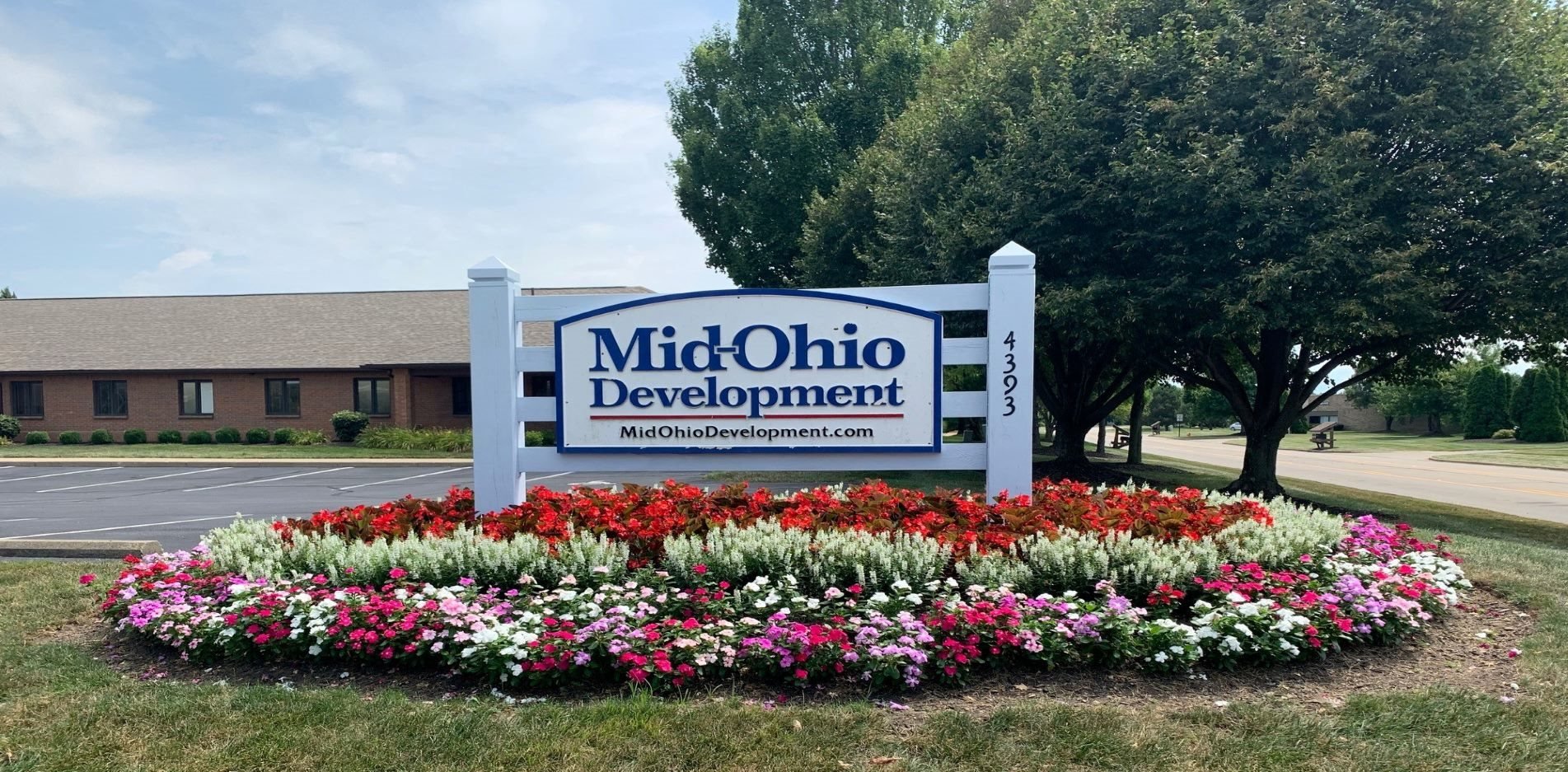 the sign in front of the office is surrounded by flowers