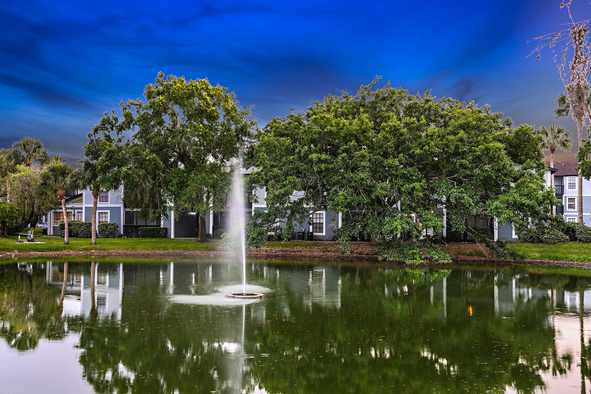 View of Brookside Manor Lake with water fountain and rich blue sky
