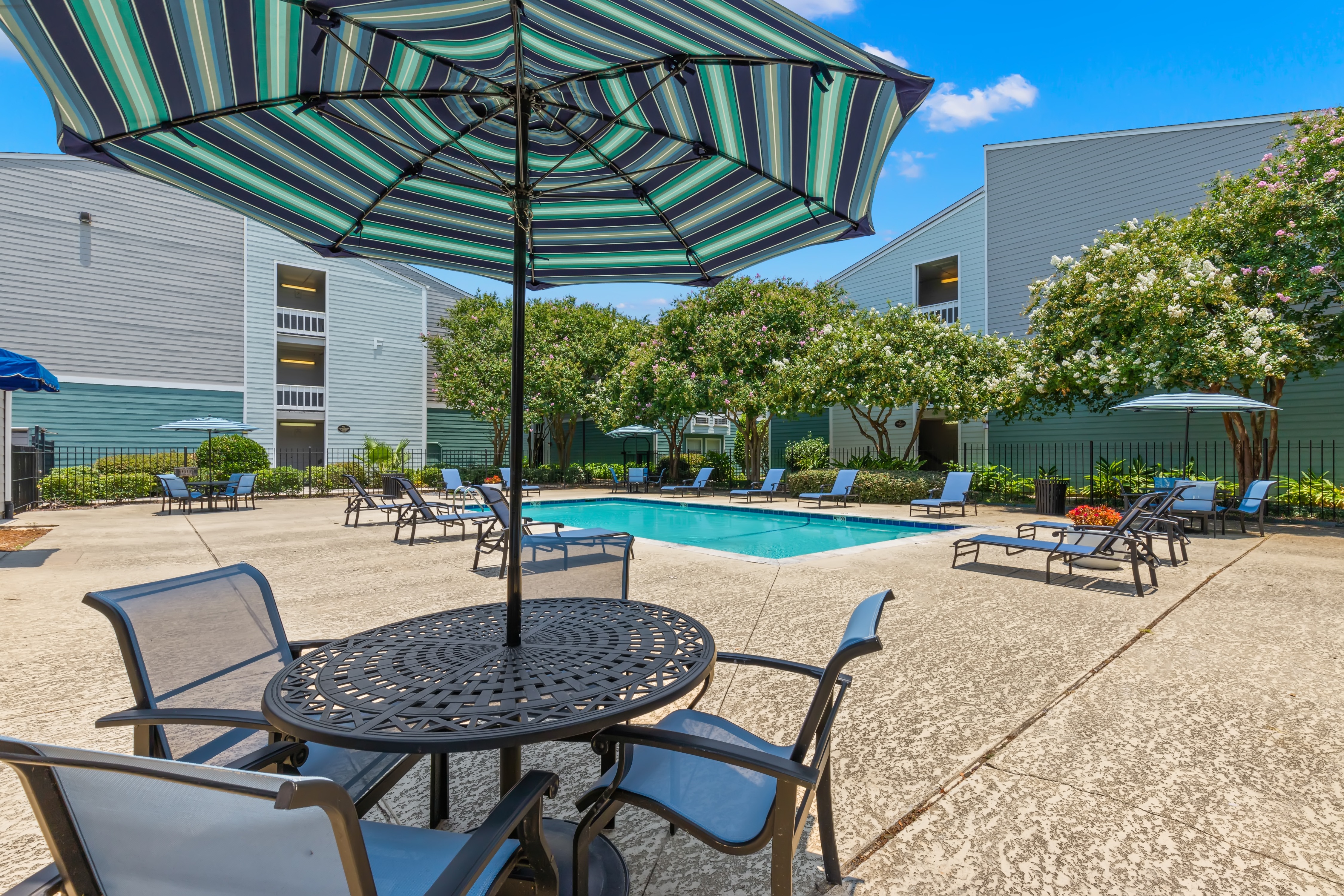 A patio with a table, chairs and an umbrella.