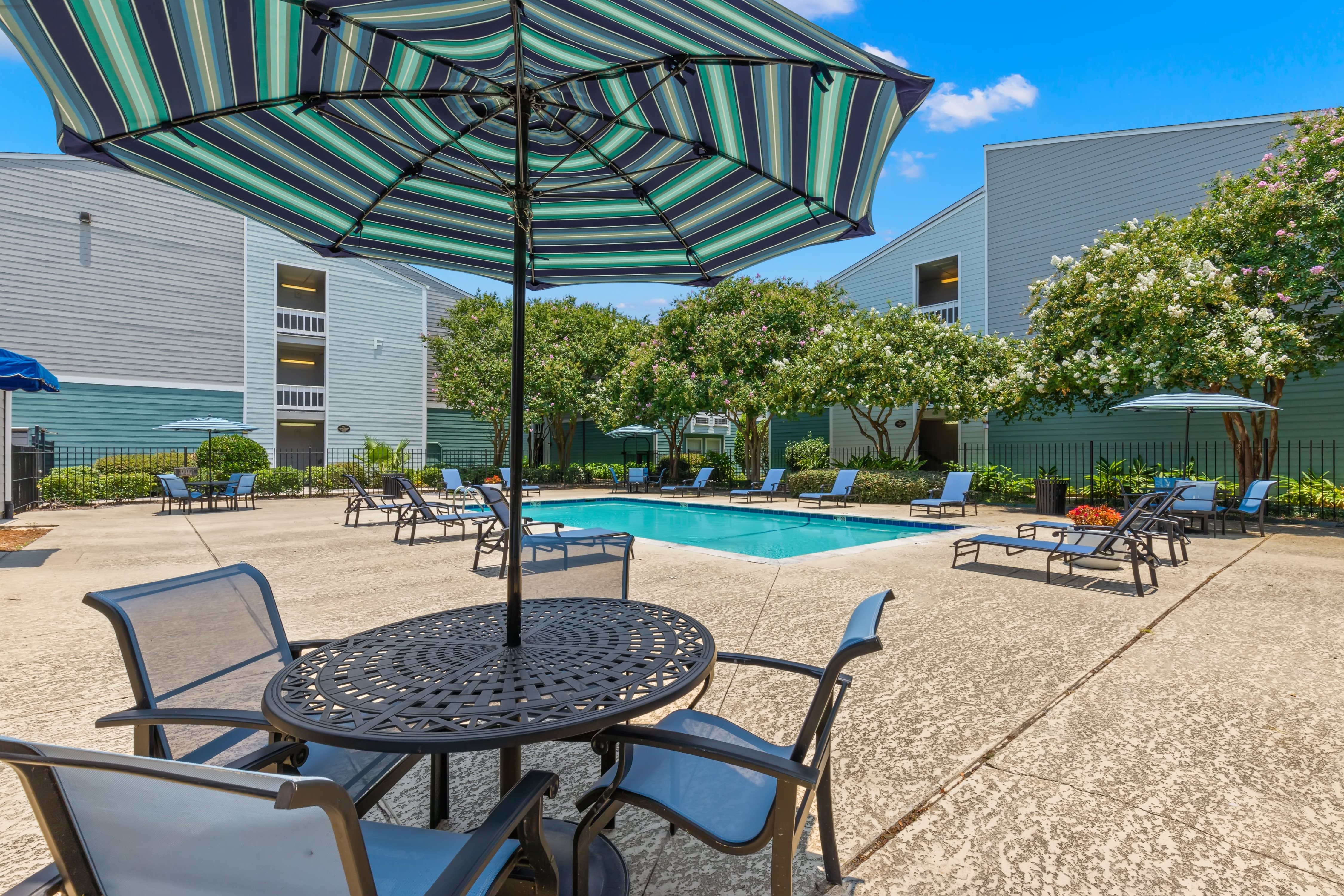 A patio with a table, chairs and an umbrella.