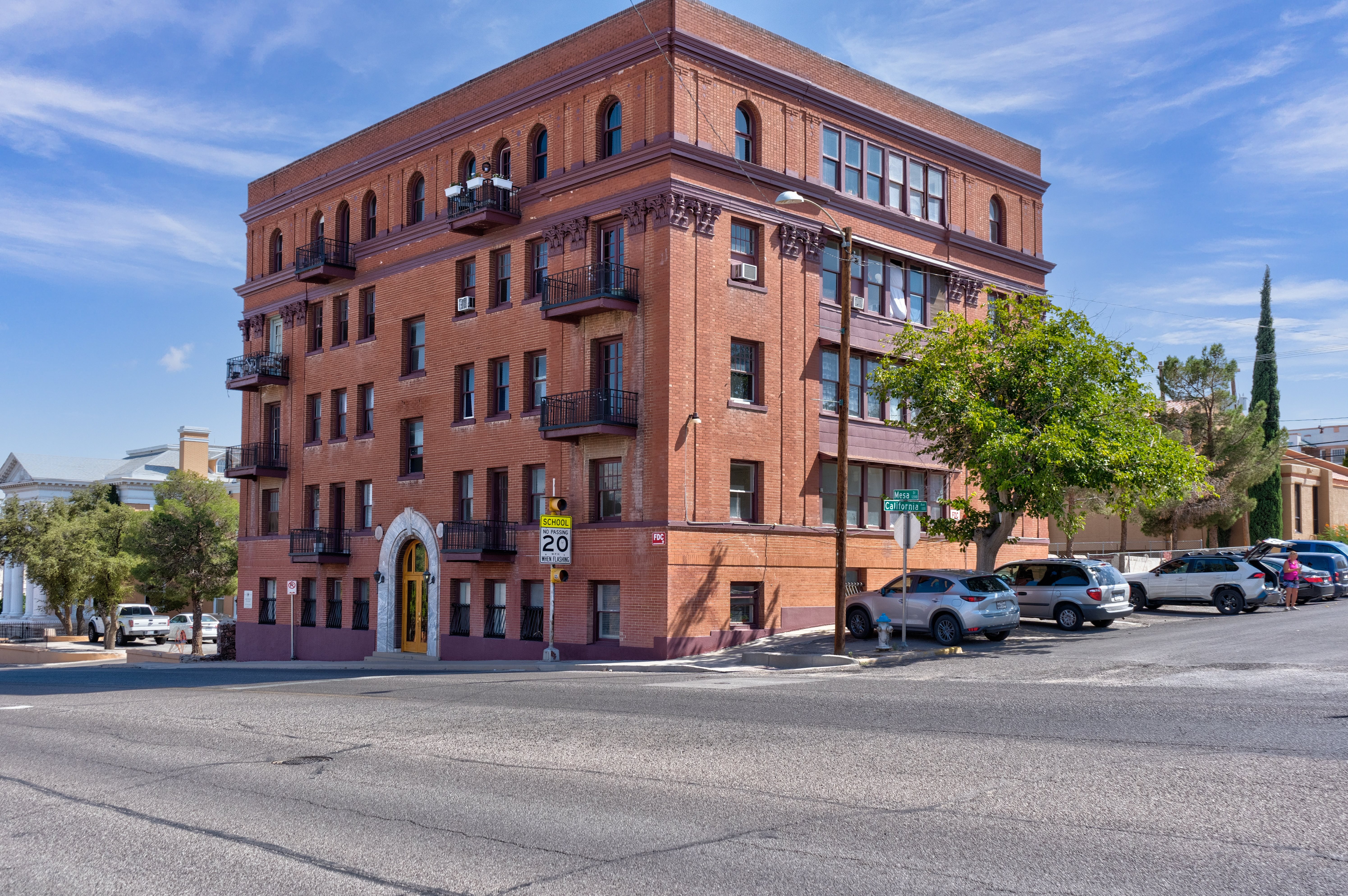 A red brick building with a yellow door and balconies.