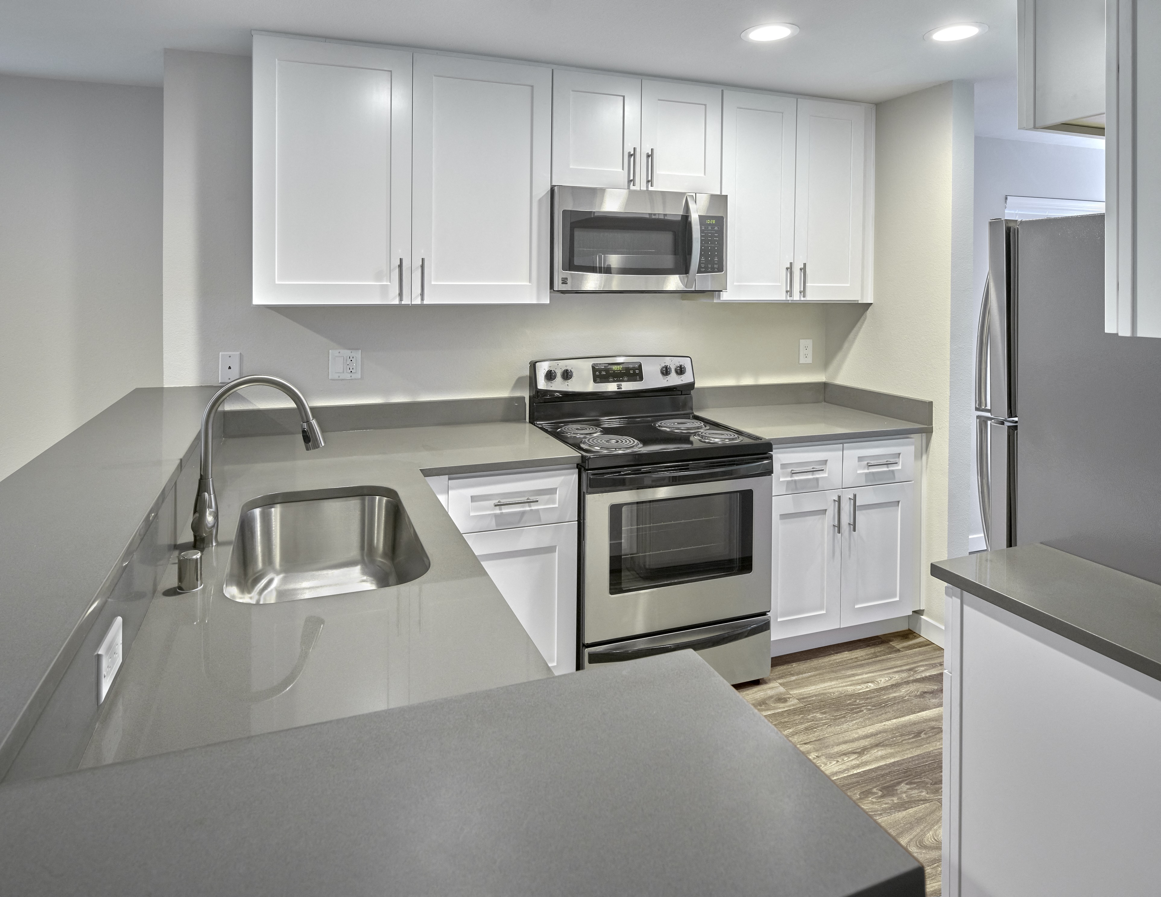 an empty kitchen with white cabinets and stainless steel appliances