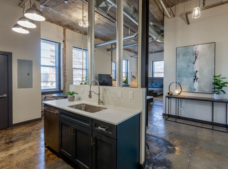 Industrial Style Apartment with Exposed Concrete and Ducts, Kitchen with Breakfast Bar with Stools and Blue Cabinets Under White Counters