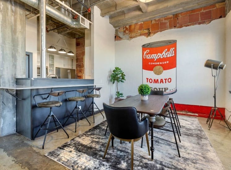 Industrial Style Apartment with Exposed Concrete and Ducts, Breakfast Bar off of Kitchen with Stools, Dinning Room with Dinning Table and Chairs on Area Rug with Decorations
