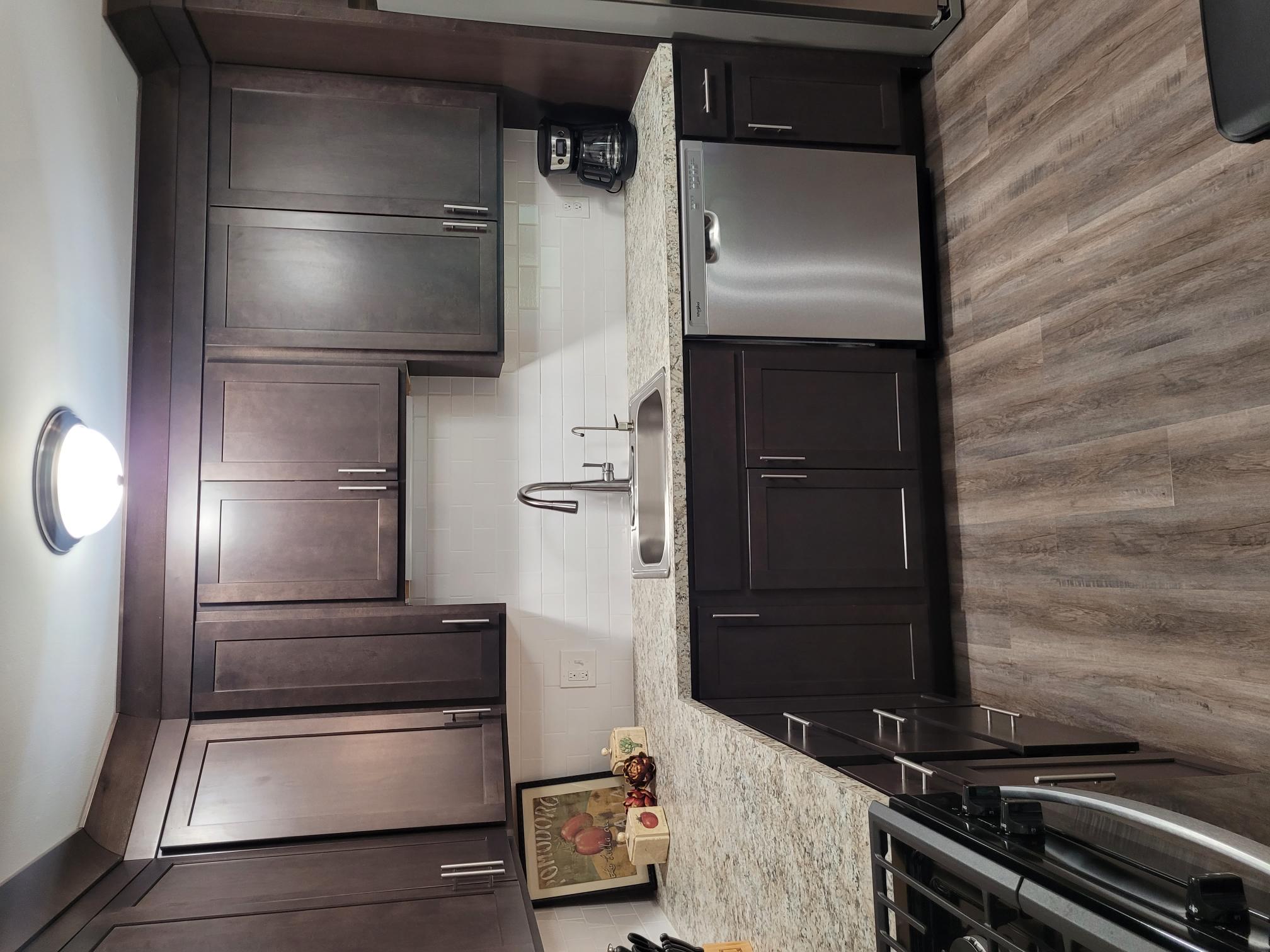 A kitchen with dark brown cabinets and a stainless steel oven.