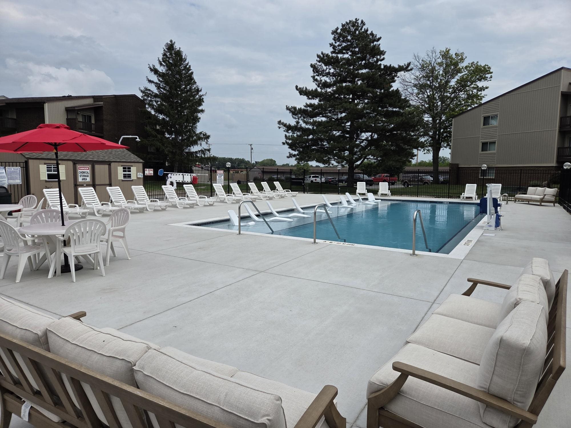 A pool area with chairs and umbrellas.