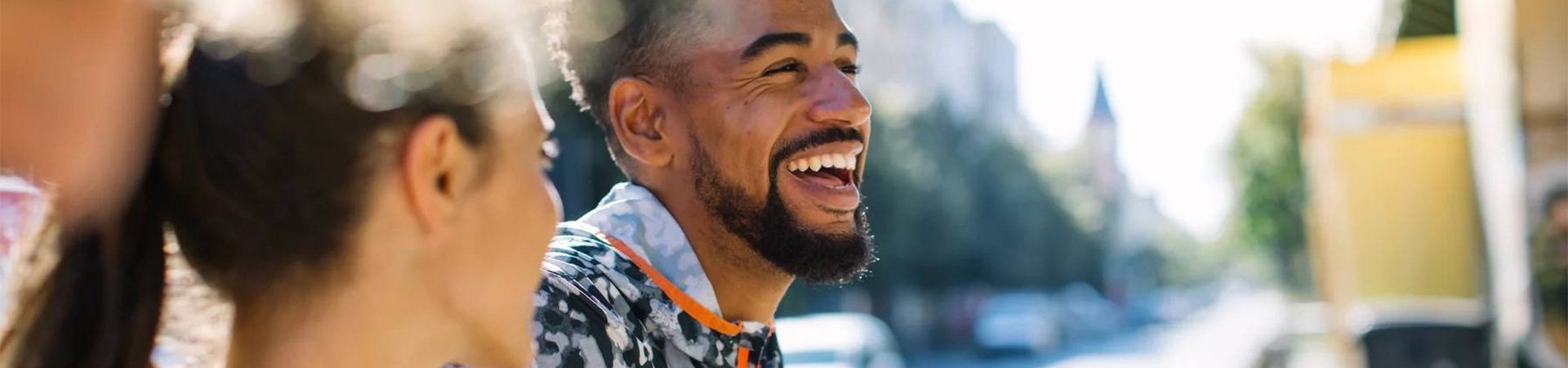 A man with a beard is laughing while wearing a patterned shirt.
