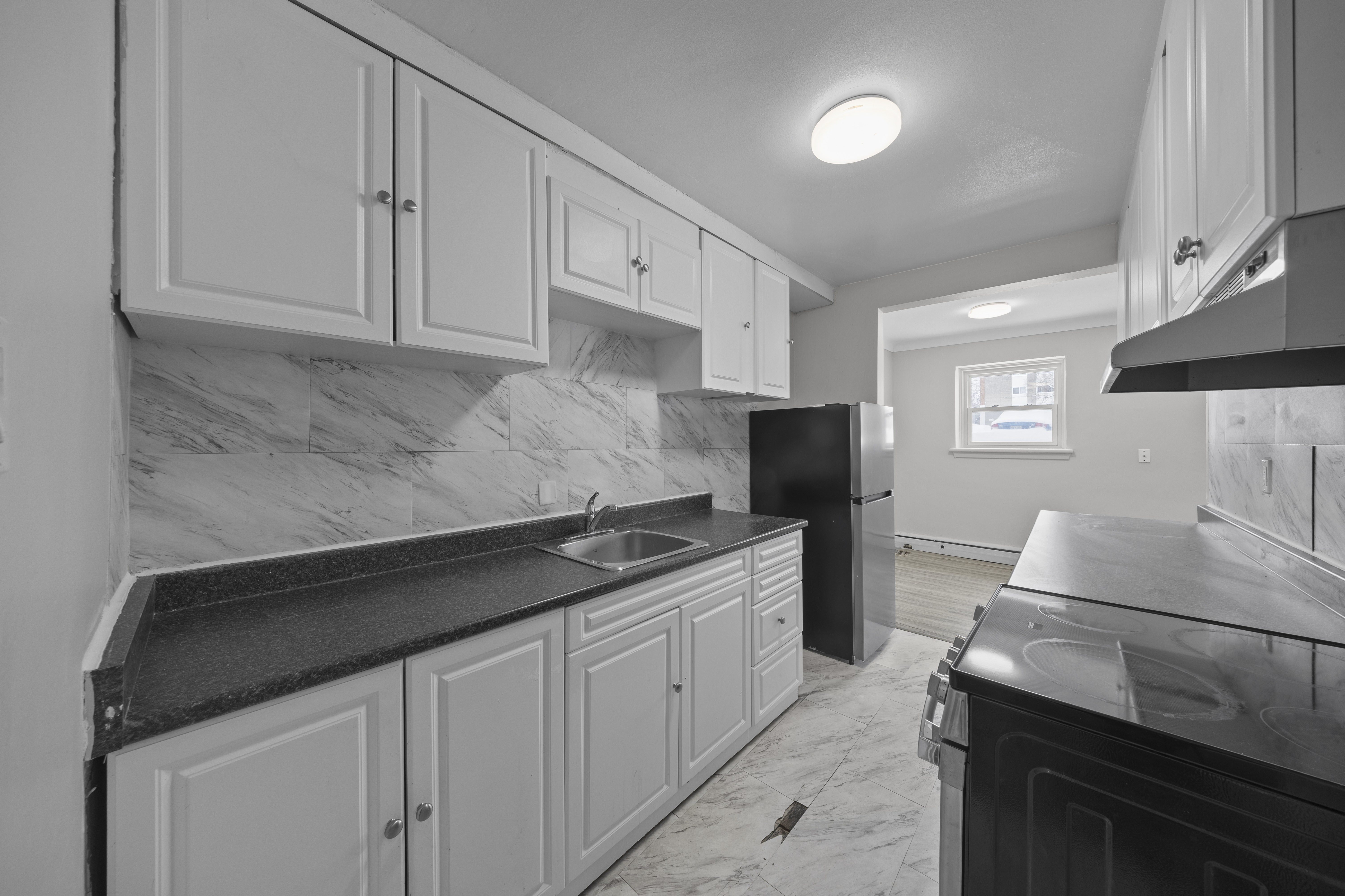 A kitchen with white cabinets and black countertops.