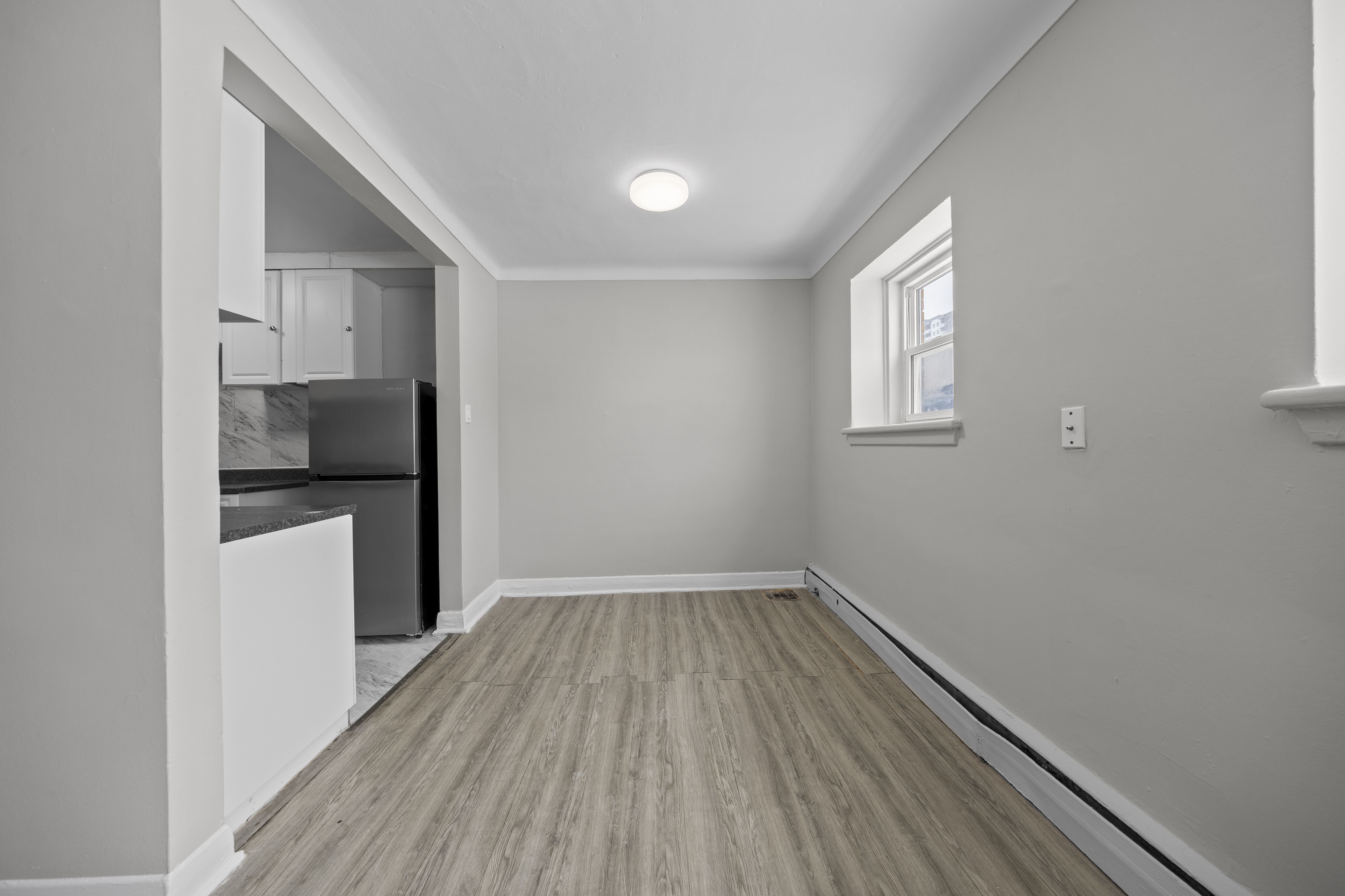 A kitchen with a refrigerator, cabinets, and a window.