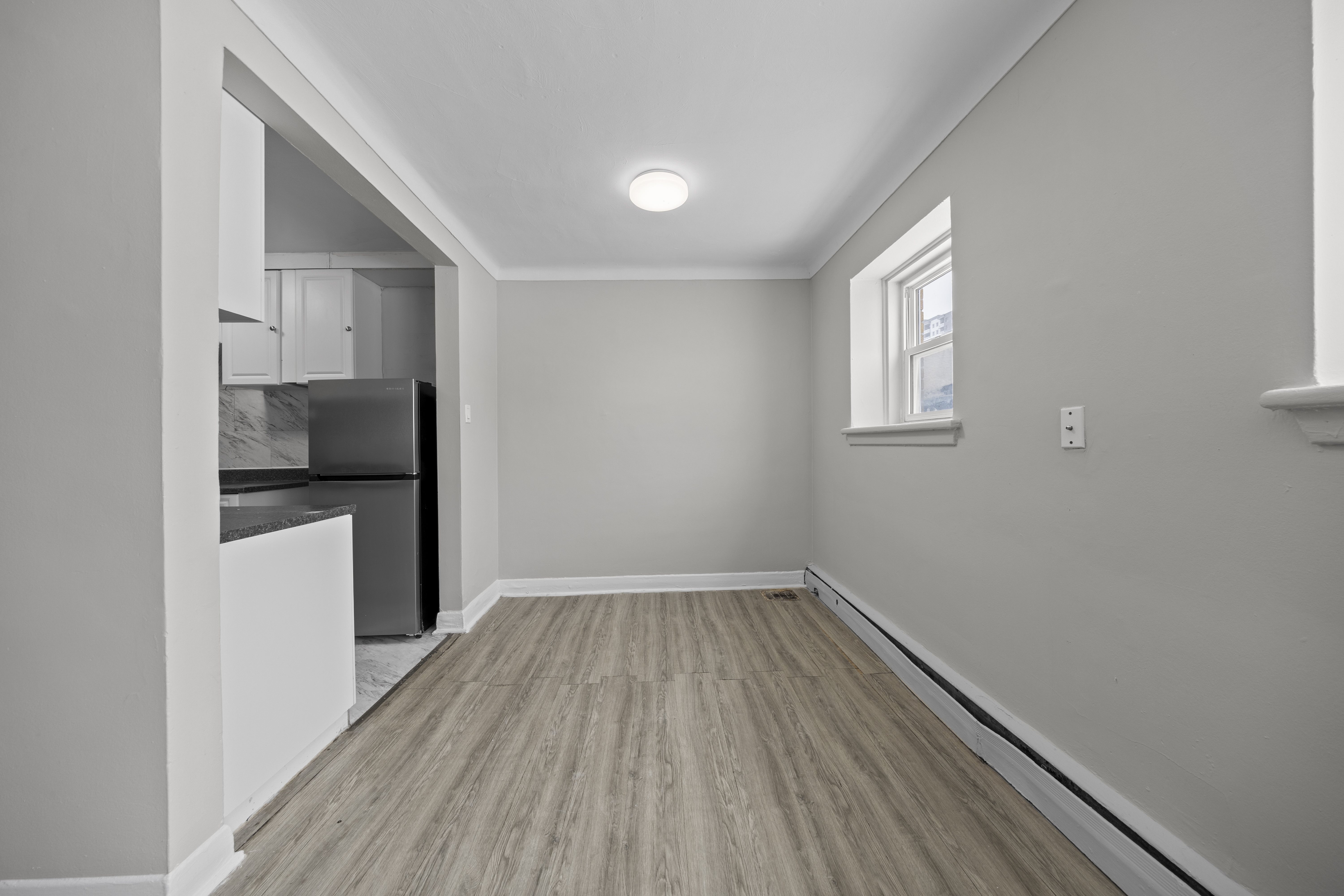 A kitchen with a refrigerator, cabinets, and a window.