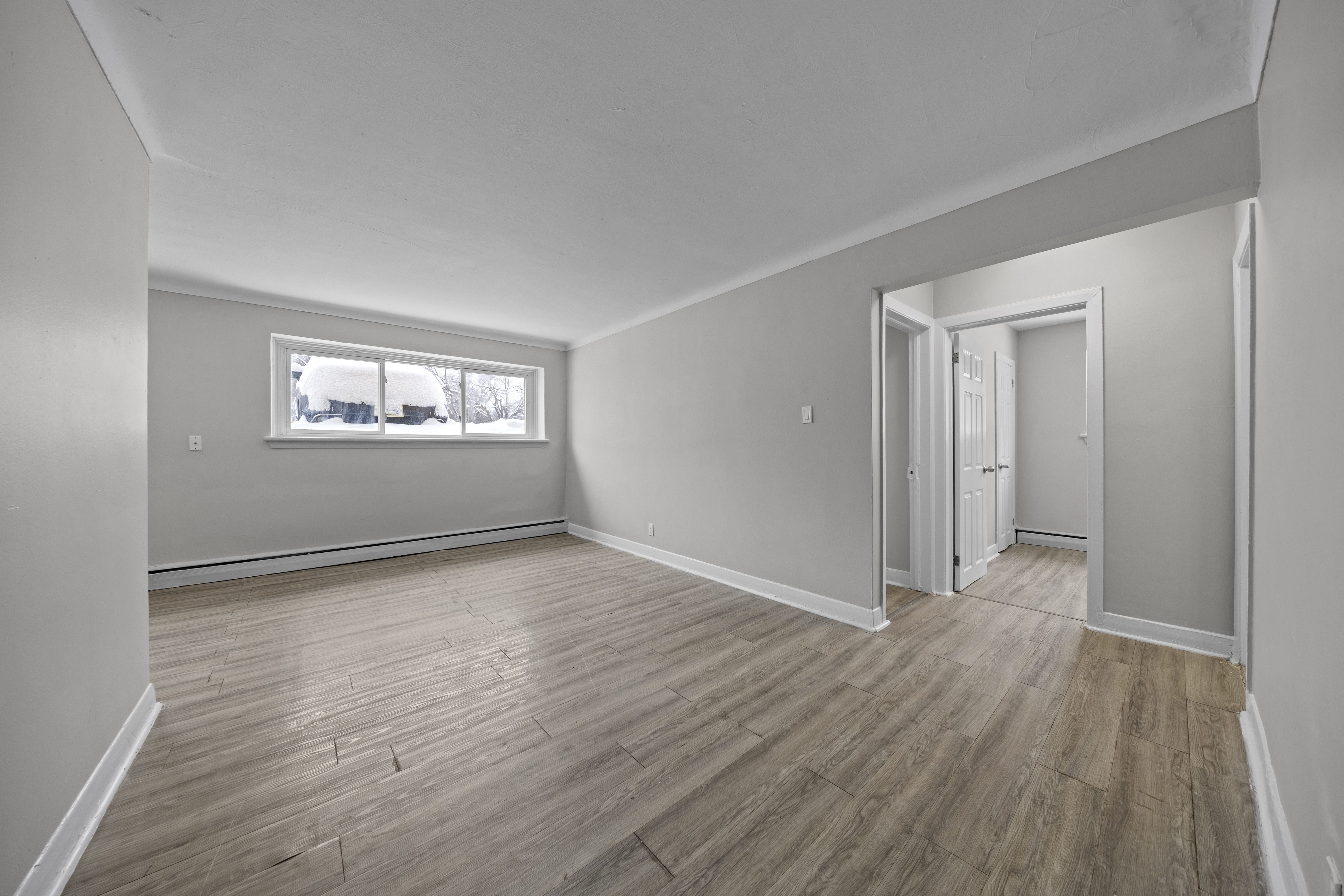 A room with wooden flooring and a window showing a snowy landscape outside.