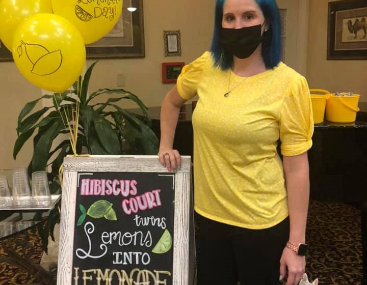 Team Member Poses With A Poster at Hibiscus Court, Melbourne, FL, 32901