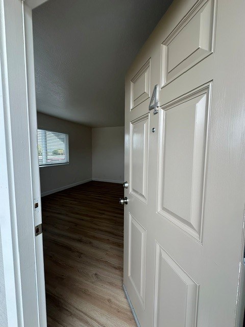 A white door with a silver handle is in a room with wooden flooring.
