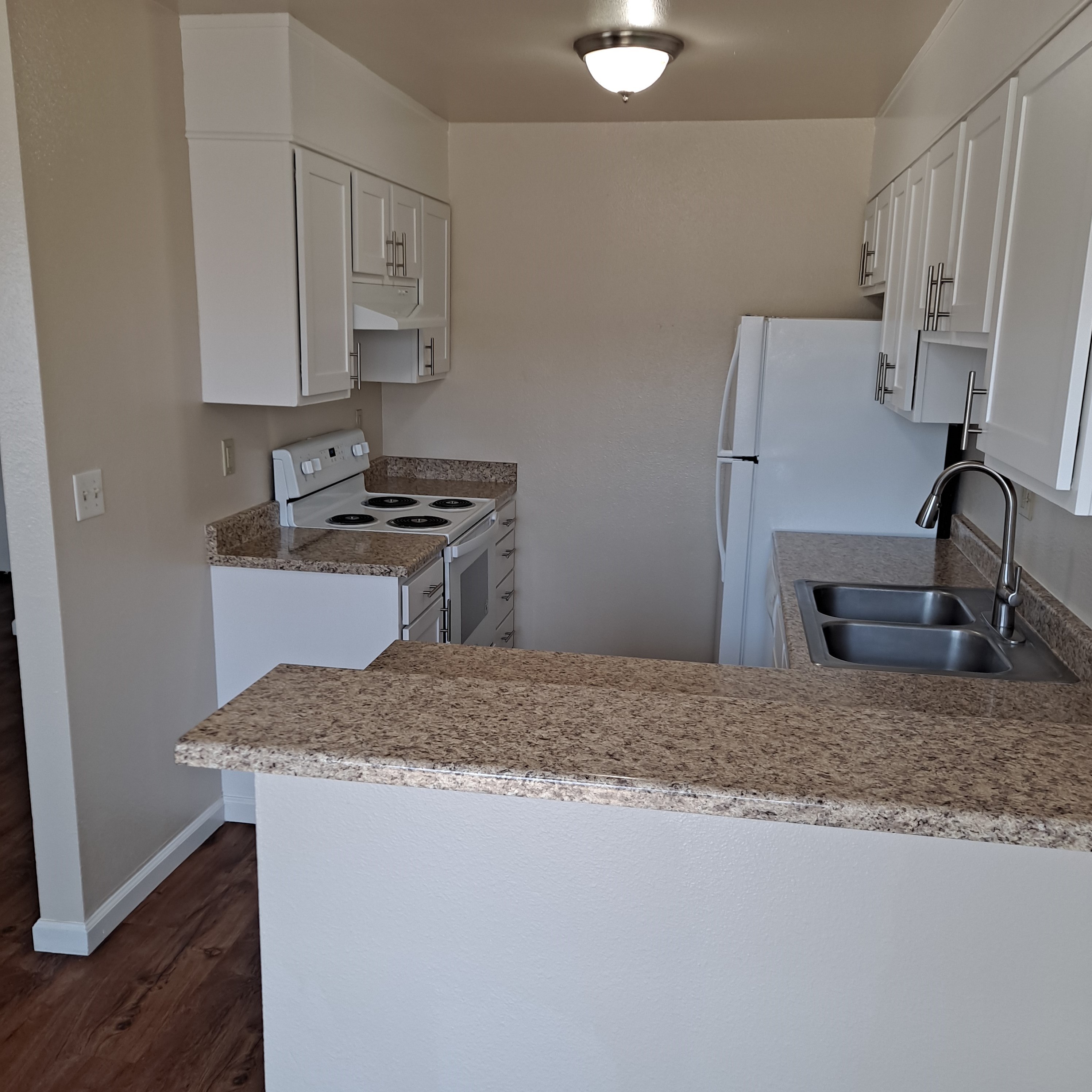 A kitchen with a granite countertop and white cabinets.