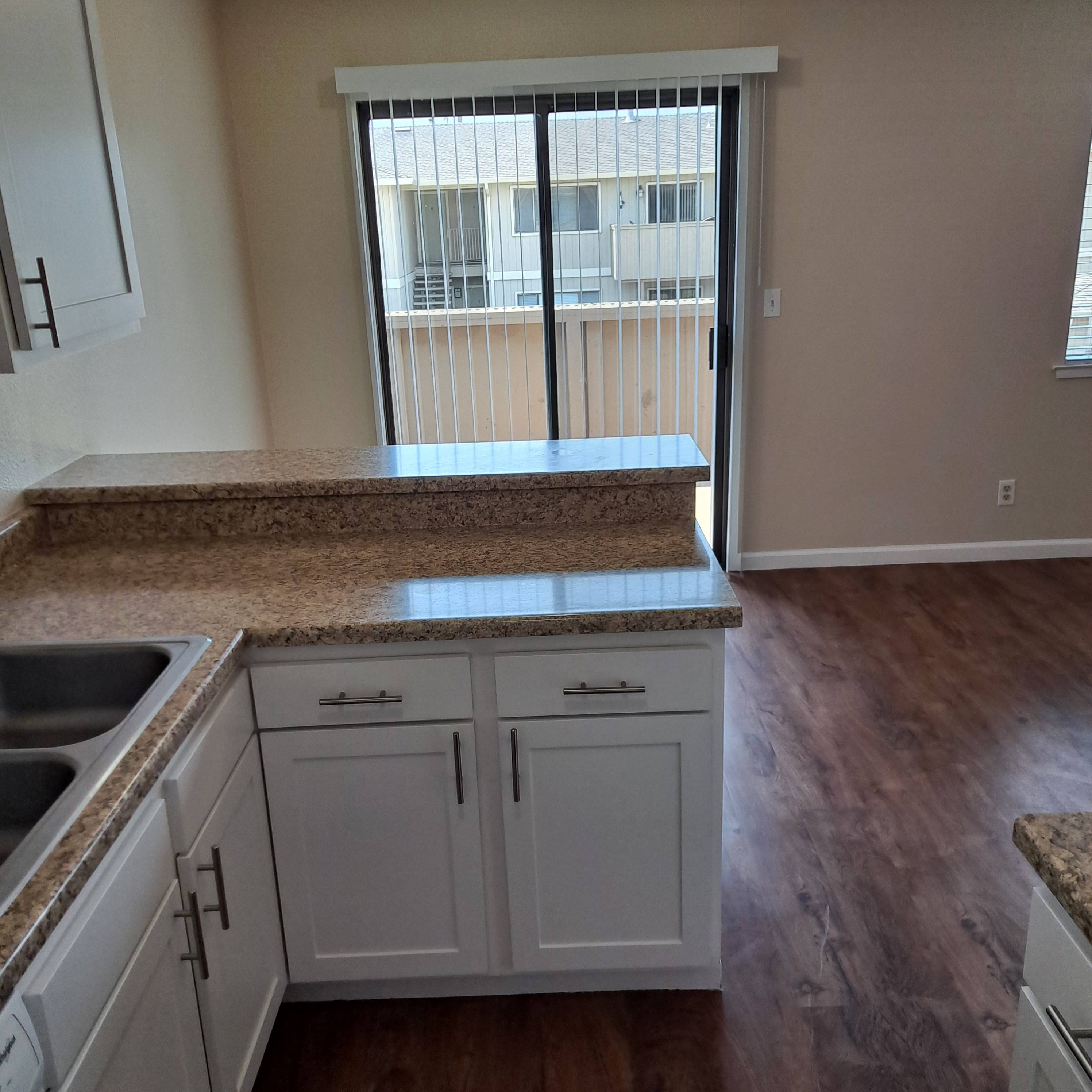 A kitchen with white cabinets and a granite countertop.